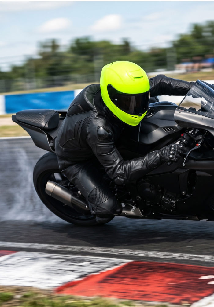 Motocyklista w limonkowym kasku w zakręcie na torze